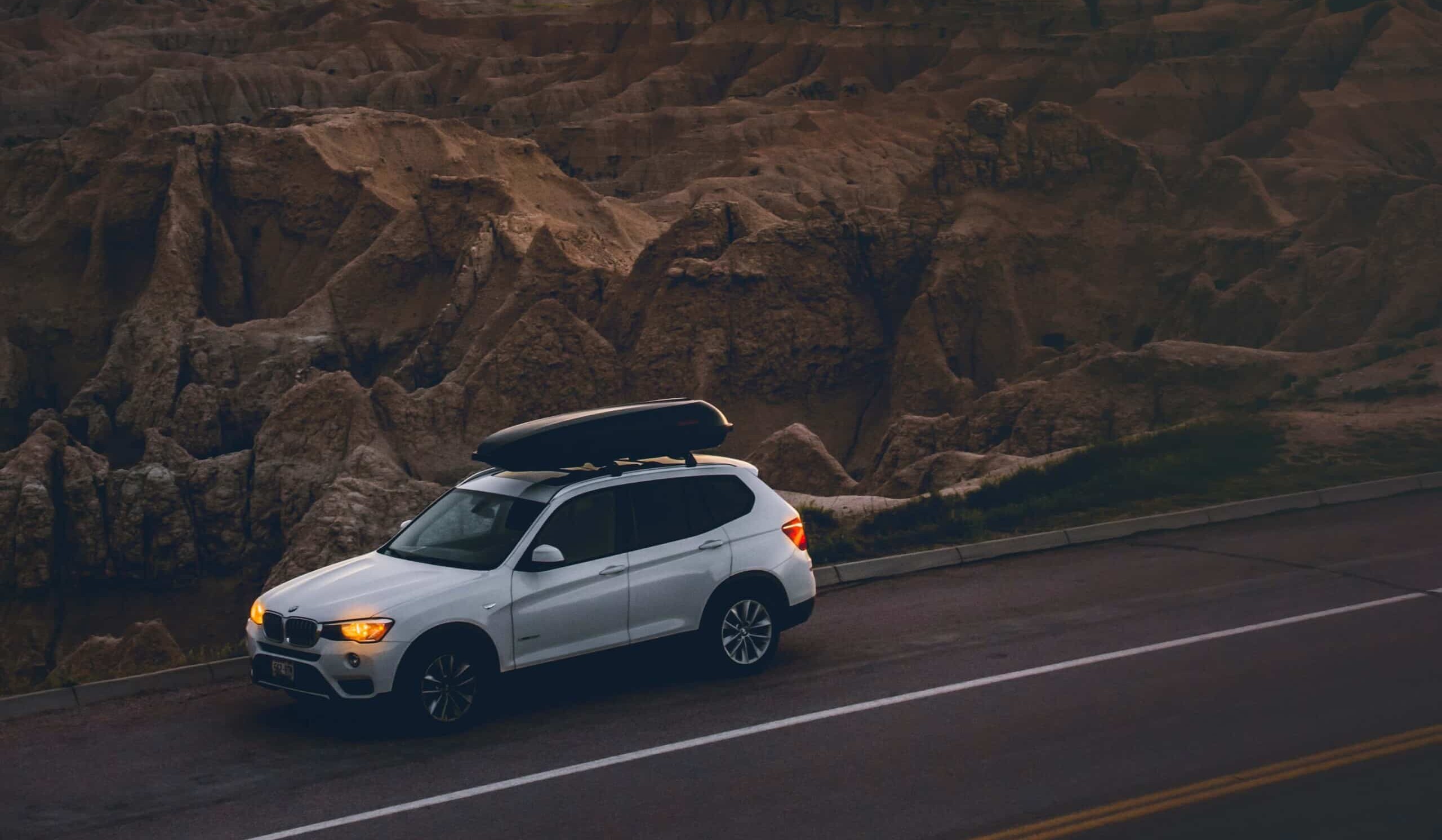 BMW SUV sitting on the side of the road in front of a beautiful sunset and view